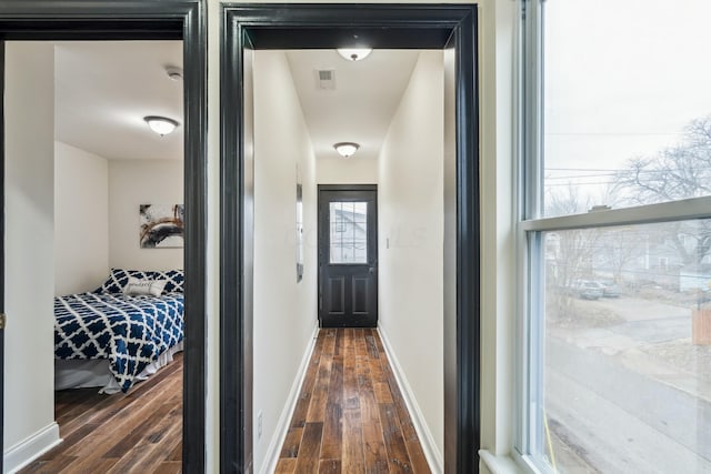 hallway featuring visible vents, dark wood finished floors, and baseboards