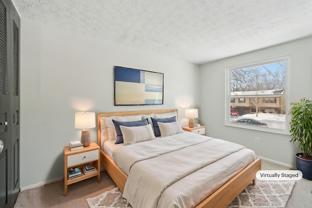 bedroom with a textured ceiling, carpet, and baseboards