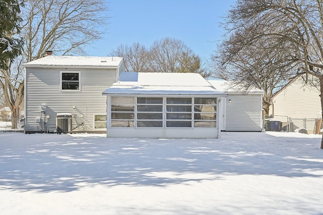 snow covered property with cooling unit, a sunroom, and fence