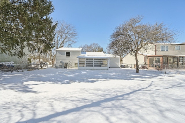 snow covered rear of property with fence and a sunroom