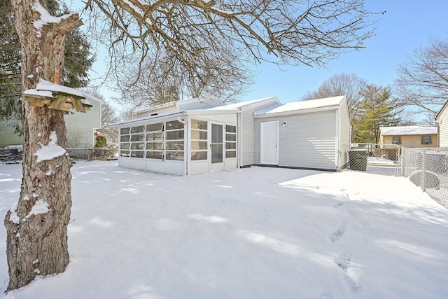 snow covered property featuring a sunroom, a gate, and fence