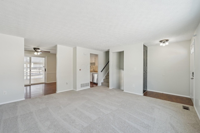 empty room with carpet, visible vents, stairway, and a textured ceiling