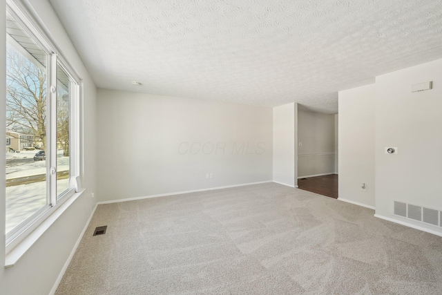 empty room with baseboards, visible vents, and carpet flooring