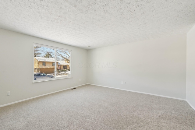 carpeted empty room featuring visible vents, a textured ceiling, and baseboards