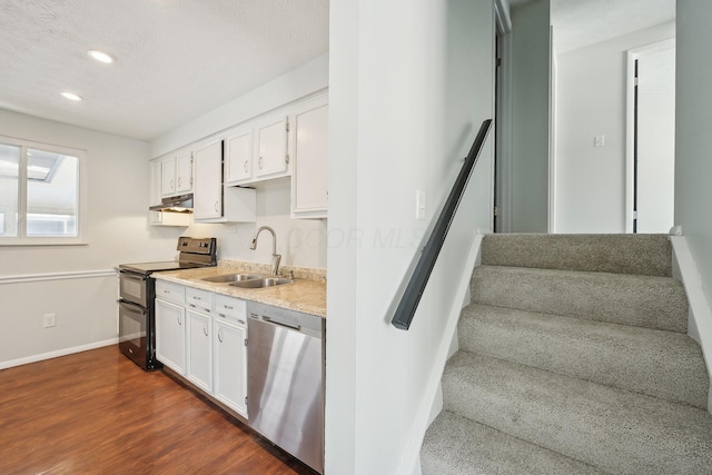 kitchen with dishwasher, under cabinet range hood, double oven range, white cabinetry, and a sink