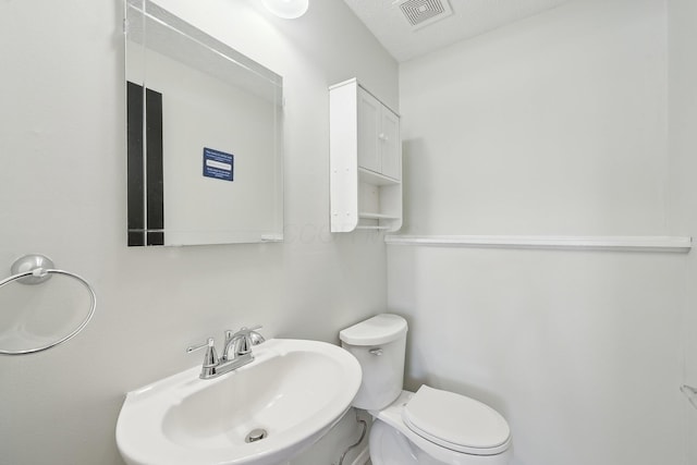 half bathroom with visible vents, a sink, and toilet