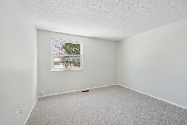 spare room featuring a textured ceiling, carpet, visible vents, and baseboards