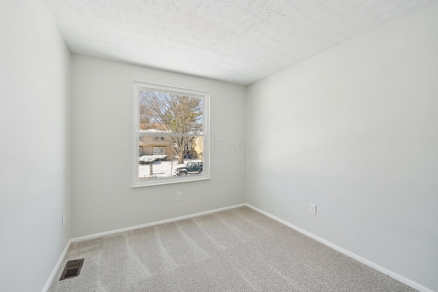 carpeted spare room with baseboards, visible vents, and a textured ceiling