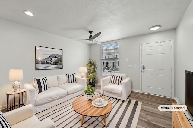 living area with baseboards, a ceiling fan, and wood finished floors