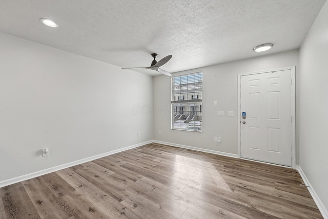 foyer entrance featuring ceiling fan, a textured ceiling, wood finished floors, and baseboards