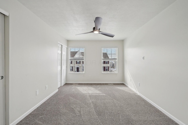 spare room with ceiling fan, carpet floors, a textured ceiling, and baseboards