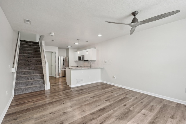 unfurnished living room with visible vents, stairway, and wood finished floors