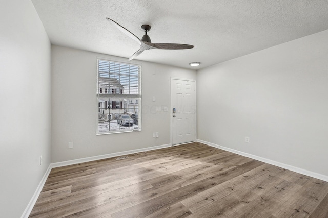 spare room featuring a ceiling fan, a textured ceiling, baseboards, and wood finished floors