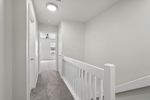 hallway featuring an upstairs landing, carpet flooring, and baseboards