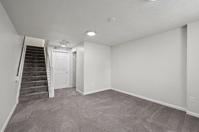 below grade area with carpet, a textured ceiling, baseboards, and stairs