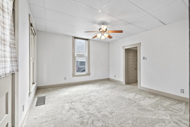 carpeted spare room featuring a paneled ceiling, visible vents, ceiling fan, and baseboards