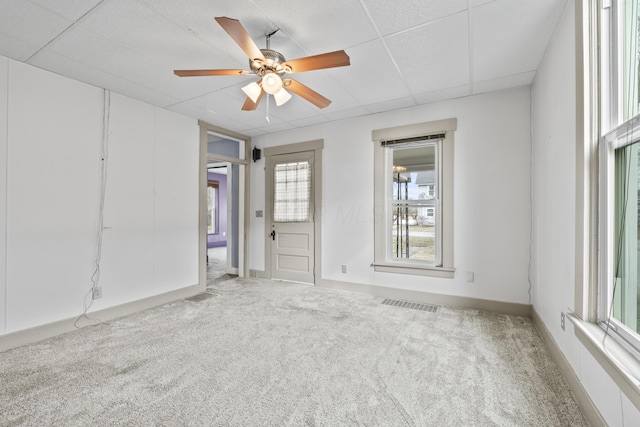 carpeted spare room featuring a ceiling fan, baseboards, visible vents, and a drop ceiling