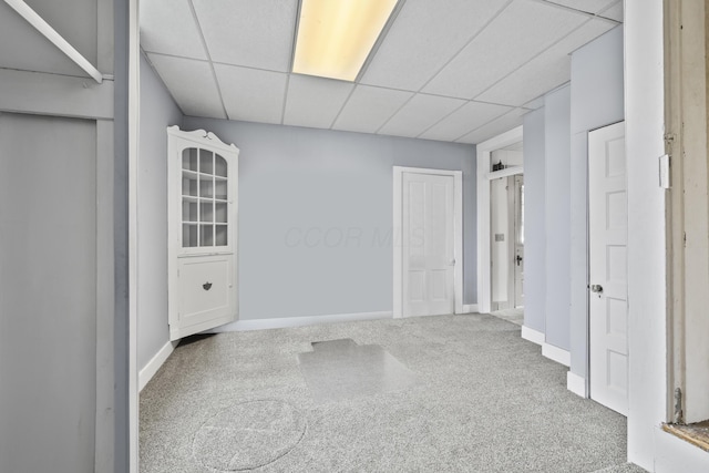 unfurnished room featuring baseboards, a drop ceiling, and carpet flooring