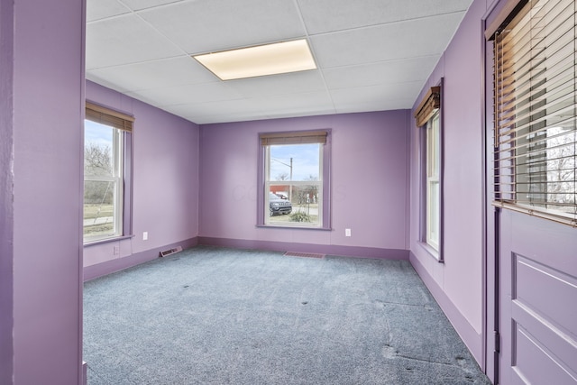 unfurnished room featuring a paneled ceiling, baseboards, visible vents, and carpet flooring