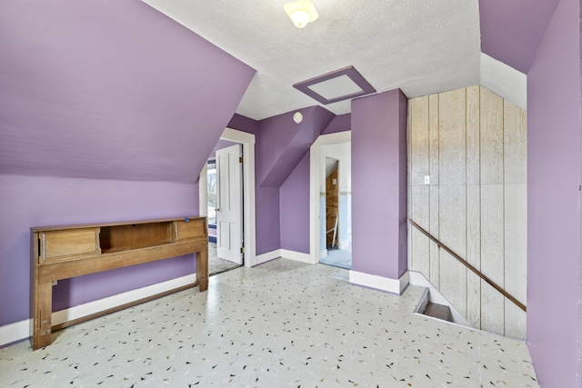 bonus room featuring a textured ceiling, vaulted ceiling, and baseboards