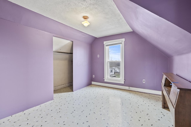 bonus room featuring lofted ceiling, carpet flooring, a textured ceiling, and baseboards