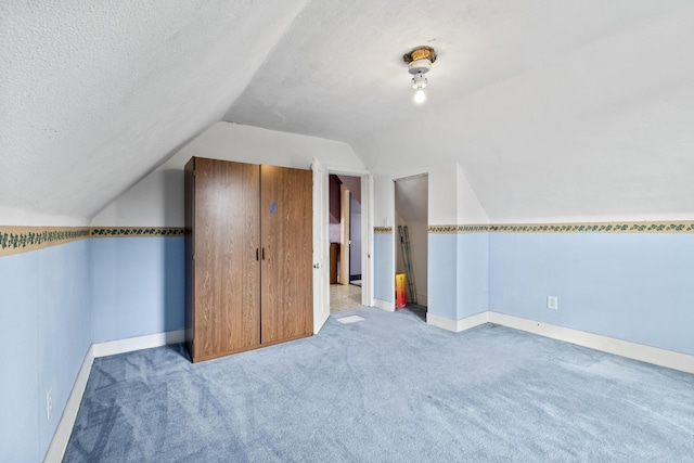 bonus room featuring carpet, vaulted ceiling, a textured ceiling, and baseboards