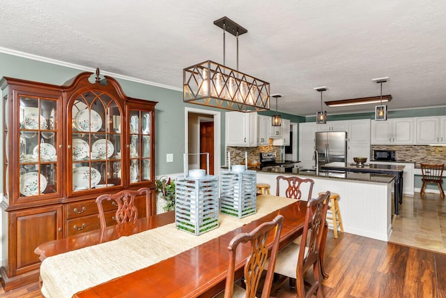 dining space with crown molding, a textured ceiling, and wood finished floors