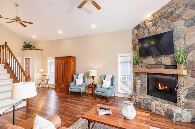 living area featuring stairs, a fireplace, high vaulted ceiling, and wood finished floors