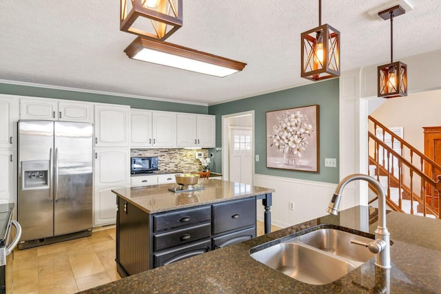 kitchen with white cabinets, a sink, dark stone countertops, black microwave, and stainless steel fridge