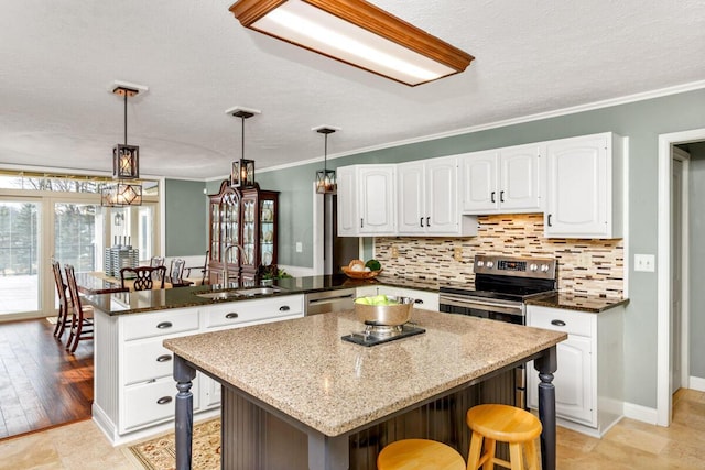 kitchen featuring a breakfast bar area, a peninsula, a sink, appliances with stainless steel finishes, and tasteful backsplash