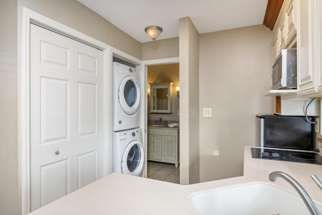 washroom with stacked washer and dryer, a sink, and tile patterned floors