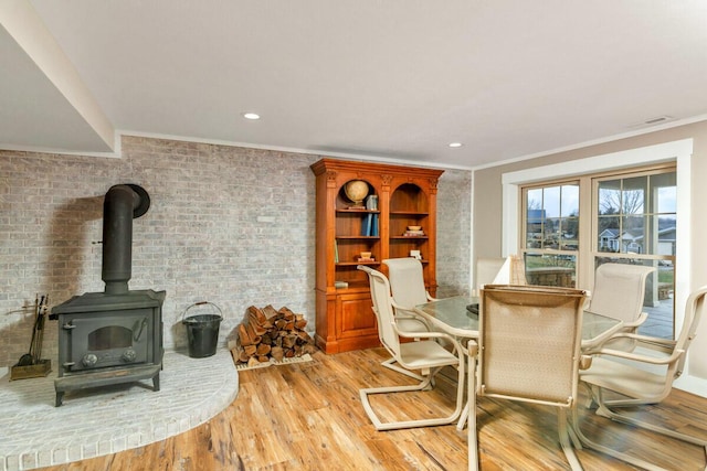 dining room featuring a wood stove, crown molding, wood finished floors, and recessed lighting