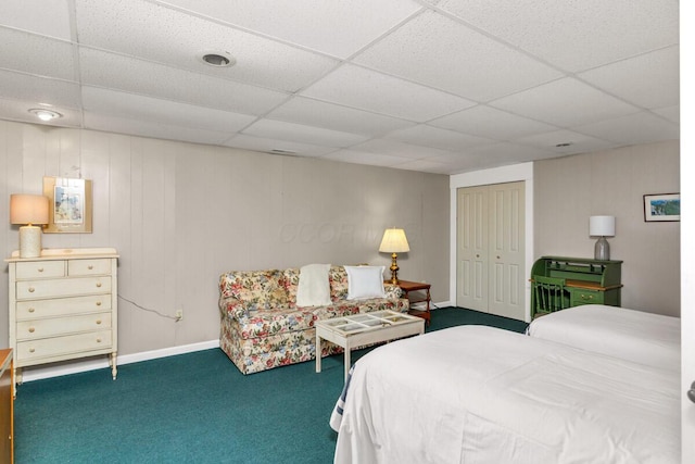 bedroom featuring carpet floors, a closet, a drop ceiling, and baseboards