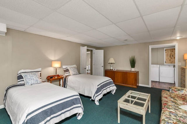 carpeted bedroom featuring separate washer and dryer, a drop ceiling, and baseboards