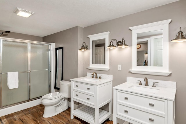 full bath featuring a stall shower, two vanities, and a sink