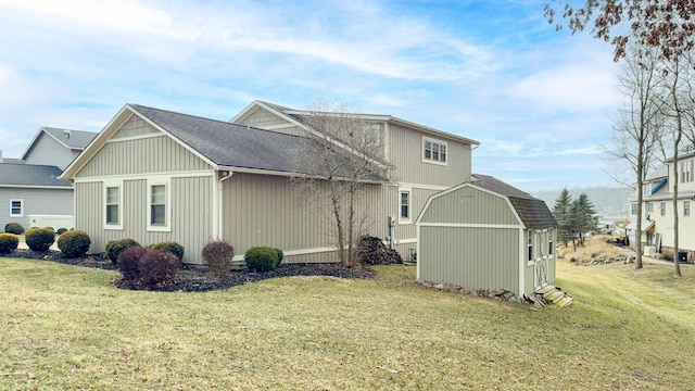 view of home's exterior featuring a shingled roof, an outbuilding, a lawn, and a storage shed