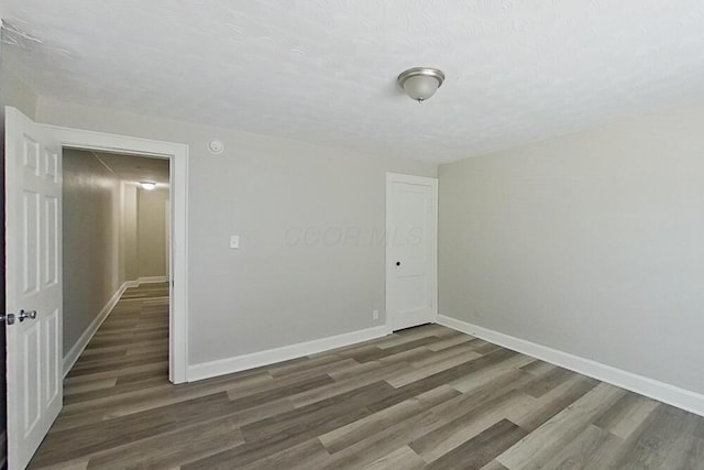 spare room with a textured ceiling, baseboards, and wood finished floors