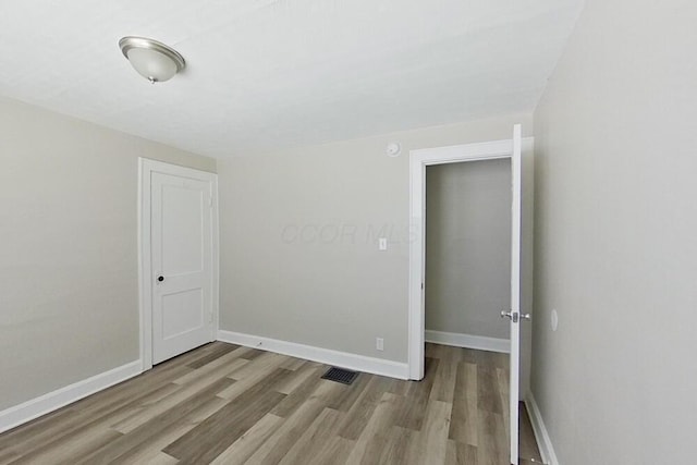 empty room with light wood-type flooring, visible vents, and baseboards