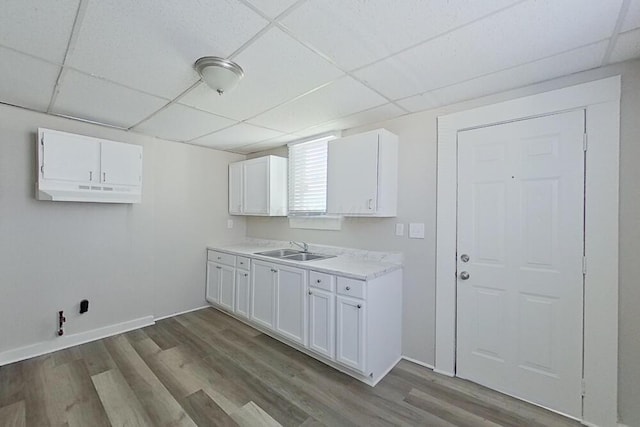 clothes washing area with dark wood finished floors, a sink, and baseboards