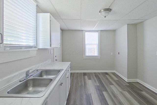 kitchen featuring dark wood-style flooring, a drop ceiling, white cabinetry, and baseboards