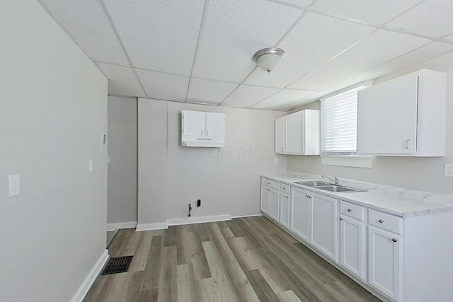 washroom featuring wood finished floors, a sink, visible vents, and baseboards