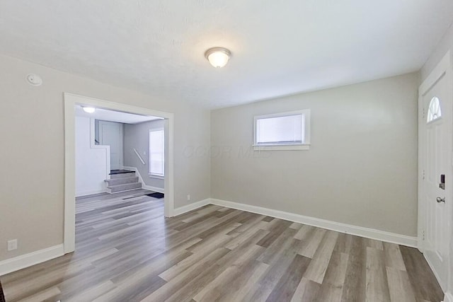 spare room featuring a healthy amount of sunlight, stairs, baseboards, and wood finished floors