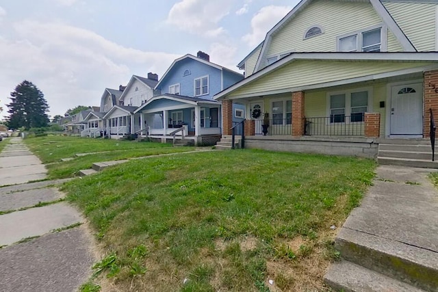 view of front of property featuring a front yard, a residential view, a porch, and brick siding