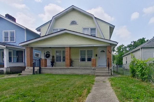 dutch colonial with covered porch, a front yard, brick siding, and a gambrel roof