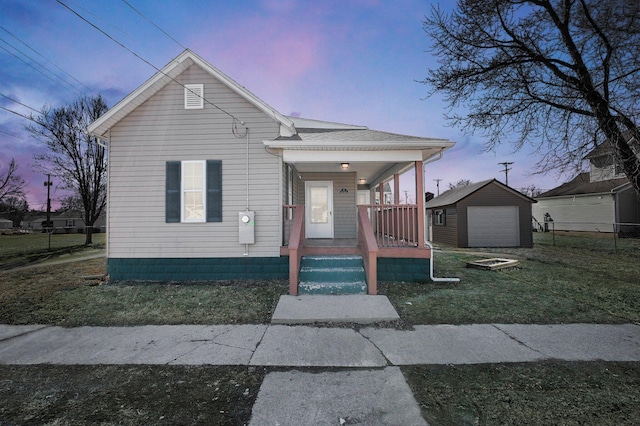 view of front of house with covered porch, a detached garage, and an outbuilding