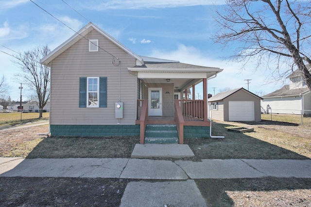 view of front of property with a garage, driveway, roof with shingles, an outbuilding, and a porch