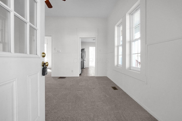 unfurnished room with carpet floors, visible vents, and a ceiling fan