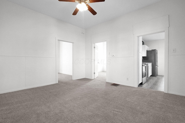 unfurnished bedroom with a ceiling fan, freestanding refrigerator, light colored carpet, and visible vents