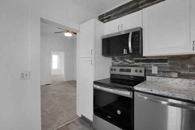 kitchen with stainless steel appliances, carpet, white cabinets, and light stone countertops