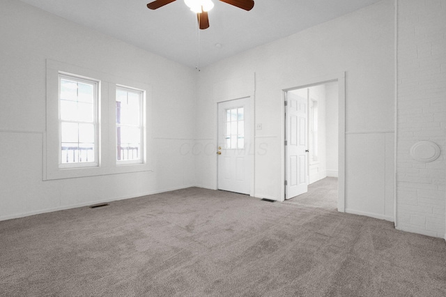 spare room with a wealth of natural light, carpet, visible vents, and a ceiling fan